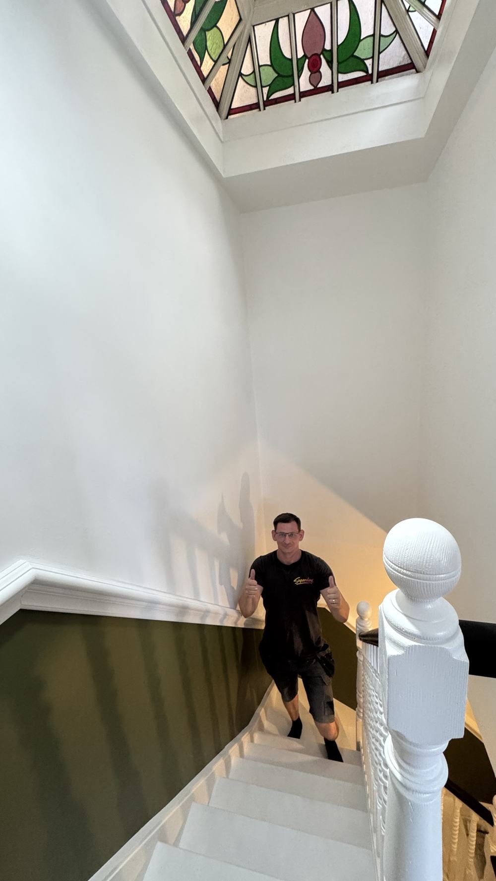 Alex on a freshly painted Victorian staircase with white spindles, green walls and a stained-glass skylight