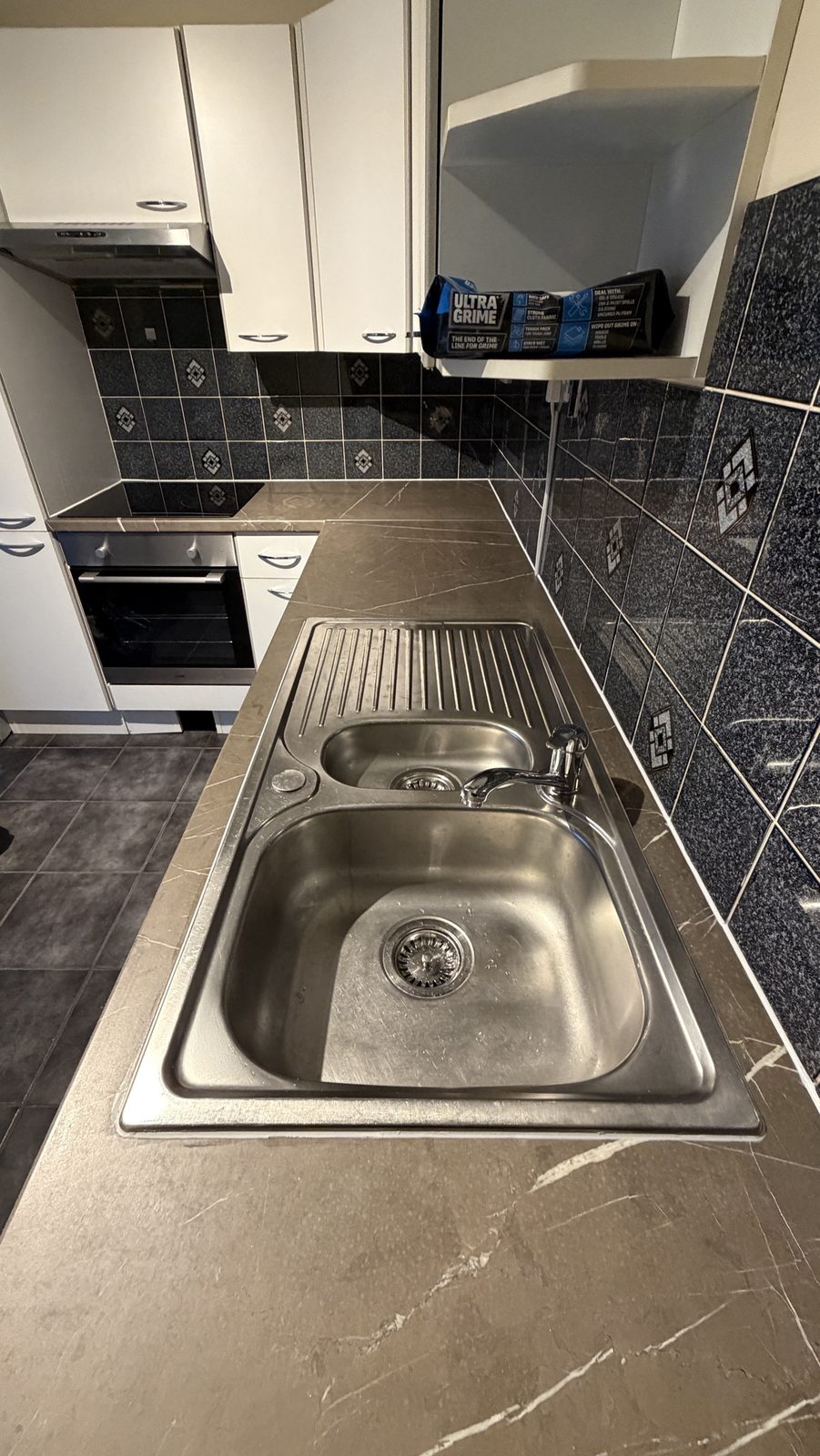Stainless steel double sink set into a stone-effect worktop, resealed around the sink and along the splashback