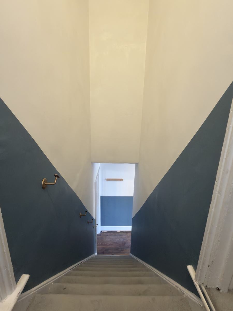Stairwell after: cream upper walls with a blue lower band