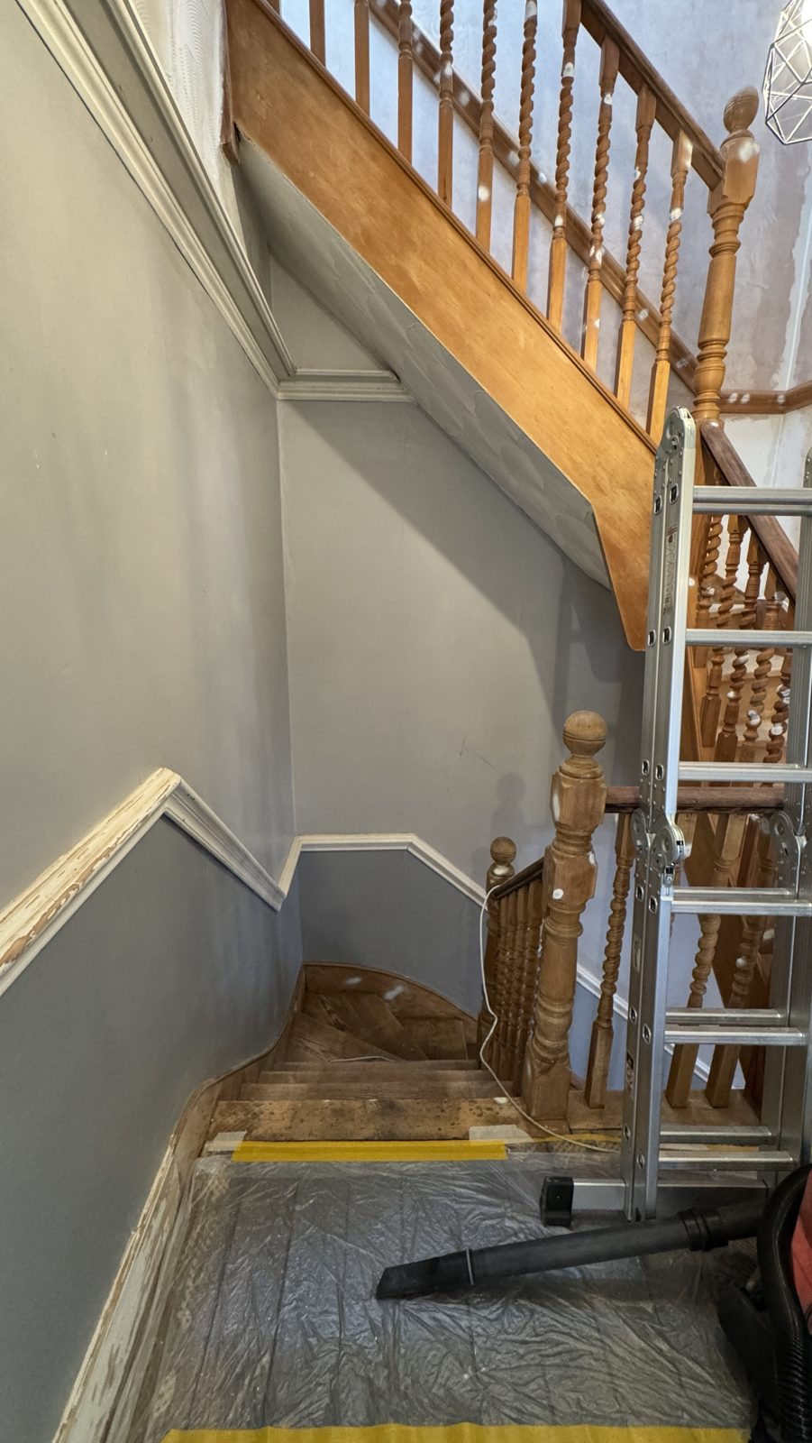 Same staircase before: orange varnished pine banister and spindles, grey walls