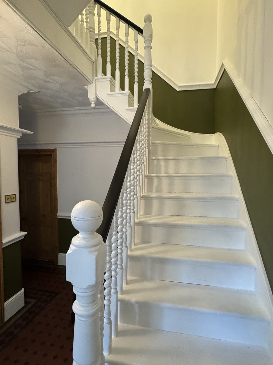 Victorian staircase after: white treads and spindles, dark handrail, green walls