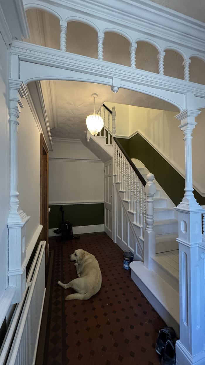 Finished Victorian hallway with white arch and spindles, green walls