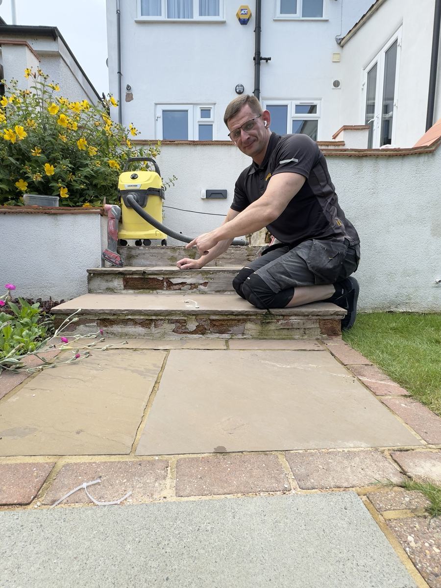 Alex kneeling by worn garden steps with broken render